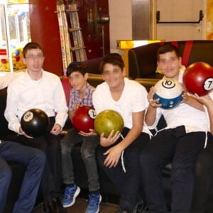 Keren Hayeled students on a bowling outing, sitting together holding their bowling balls