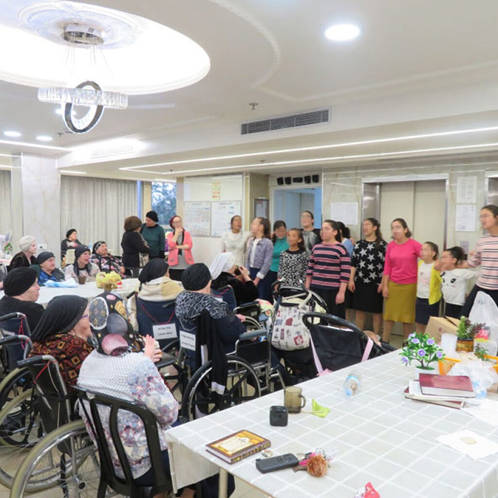 A group of Keren Hayeled students singing for elderly women at a local nursing home