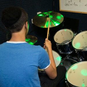 Boy playing drums in the music room at Keren Hayeled Orphanage during the extracurricular music program
